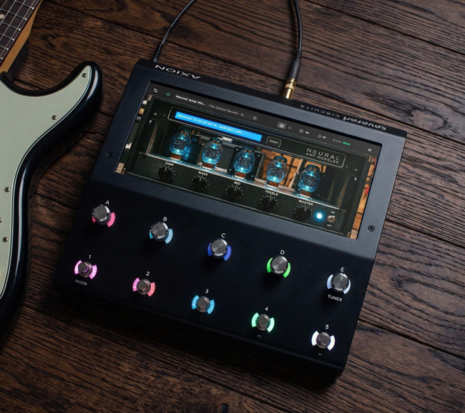 Severed Axion sobre mesa de madera, pedalera negra con pantalla que muestra Neural Amp Modeler y luces junto a una guitarra
