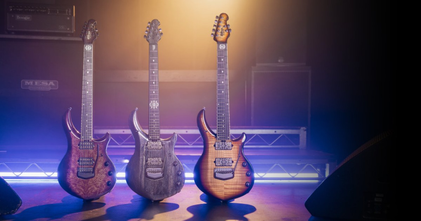 Tres guitarras Majesty BFR de pie sobre un escenario con cajas y cabezal Mesa/Boogie al fondo bajo luz morada y ámbar