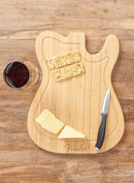 La tabla de cortar Fender Telecaster en uso con galletas, queso y cuchillo encima.
